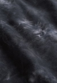 Czarna tkanina o miękkiej, teksturowanej powierzchni z subtelnymi wzorami szarych marmurek. Materiał wydaje się lekki i luźno układający.