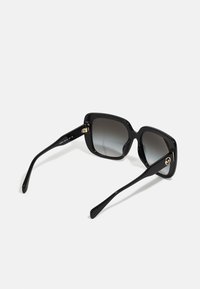 Ochelari de soare negri în formă de pătrat, cu lentile degrade, rame lucioase și accente aurii pe brațe. Textură netedă și design robust.