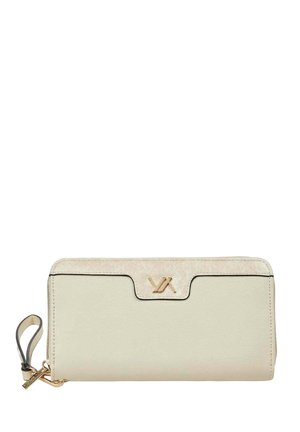 Cartera beige de cuero con cremallera alrededor, correa para la muñeca y detalle de logo metálico en tono dorado en el centro superior.
