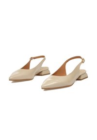 Zapatos slingback beige con puntera puntiaguda, hechos de cuero suave. Cuentan con un tacón bajo y un tirante estrecho en el tobillo con hebilla.