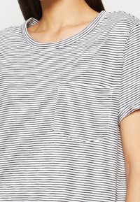 Randig kortärmad skjorta i vitt och marinblått. Har en rundad halsringning och en bröstficka. Mjuk tyg med en avslappnad passform.