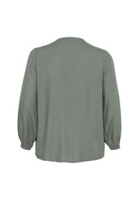 Green blouse with long sleeves, round neckline, and textured pattern of small dots. Features gathered cuffs at sleeve ends.