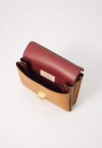 Lædertaske med en maroon topflap og en tan bund. Har en guld-tone clasp og indre label. Glat tekstur og struktureret design.