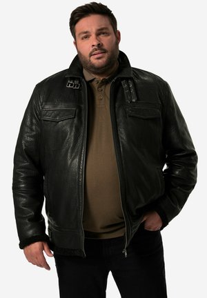 Black leather jacket with textured finish, front zip closure, two chest pockets, and shearling-lined cuffs. Worn over a brown shirt.