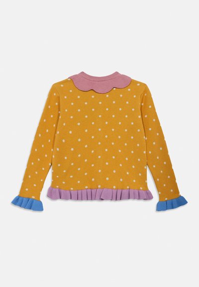 Žltý sveter s bielymi bodkami, ružovým zubatým golierom a volánovým lemom v fialovej a modrej farbe. Dlhé rukávy s kontrastnými manžetami.