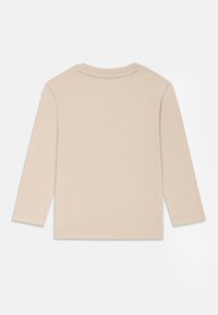 Μπεζ μακρυμάνικη μπλούζα φτιαγμένη από μαλακό βαμβάκι με στρογγυλή λαιμόκοψη, διαθέτει ελάχιστες ραφές και ίσια στρίφωμα.