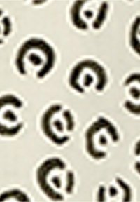 Surface beige avec un motif répétitif de taches de léopard noires et blanches irrégulières, disposées régulièrement et de forme abstraite.