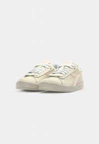 White leather low-top sneakers with light pink accents, grey laces, and textured rubber soles. Smooth surface and minimal design details.