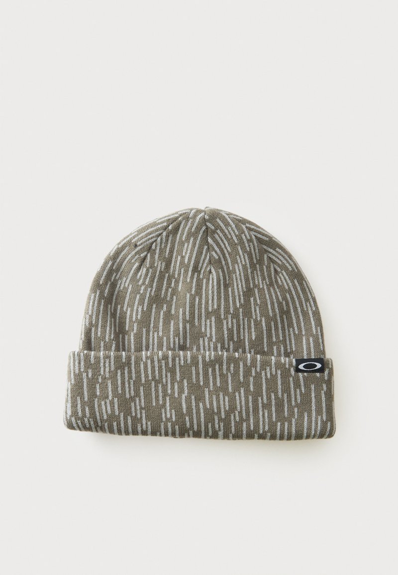 Bonnet tricoté gris avec des motifs en tirets blancs et une petite étiquette logo Oakley noir et blanc sur le revers.