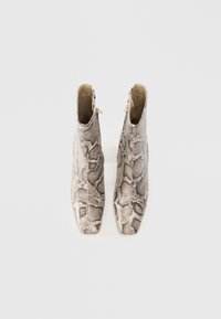 Une paire de bottines montantes avec un motif en cuir de serpent beige et gris, à bouts carrés et avec des zips latéraux, vue d'en haut sur un fond blanc.
