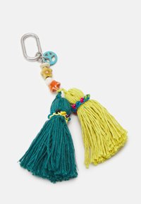 Avainrenkaassa on kaksi tupsua: yksi teal-värinen ja toinen keltainen. Siinä on helmiä, rauhansymboli-riipus sekä erilaisia värikkäitä yksityiskohtia.