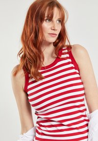 Rood-wit gestreepte tanktop met een geribbelde textuur en ronde hals. Heeft brede schouderbanden en een strakke pasvorm.