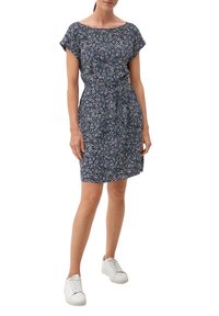 Blå blommig klänning med korta ärmar, åtsittande midja och knälång kjol, tillverkad av lättviktsmaterial, i kombination med vita sneakers.