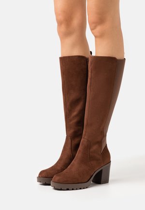 Brown suede knee-high boots with a block heel, featuring a smooth side panel and a zipper on the inner side for easy wear.