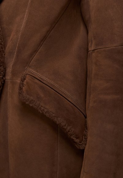 Burgundijas zamšs jaka ar aitas vilnas apkakli un apdari, diagonālām šuvēm un sānu kabatu ar mīkstu tekstūru.