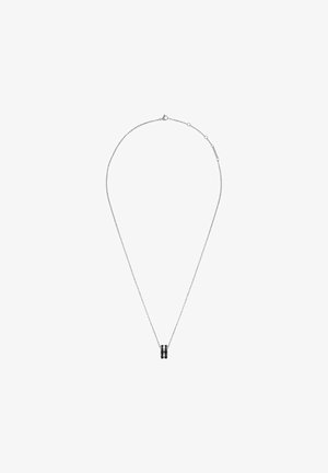 Hõbedane ketikaelakee, millel on väike silindriline ripats musta aktsendiga. Ketil on peen ja delikaatne tekstuur.