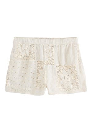 Kermanväriset puuvillahousut, joissa on joustava vyötärö ja pitsipäällysteiset sekä kukkaisella silmukkakirjailulla koristetut yksityiskohdat.