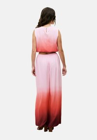 Twee-delige outfit bestaande uit een mouwloze top en wijde broek, in een kleurverloop van roze naar rood, met een sleutelgatdetail op de achterkant.