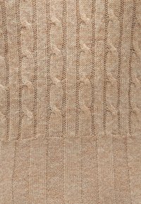 Pulover din tricot cu torsade, de culoare bej deschis, având modele alternante de torsade și nervuri. Textură moale cu un aspect confortabil.