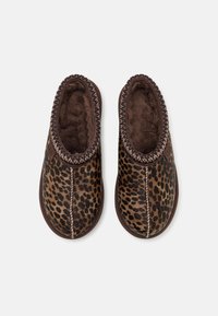 Paire de chaussons marron à enfiler avec extérieur imprimé léopard et doublure intérieure douce et pelucheuse, vus de dessus sur fond blanc.