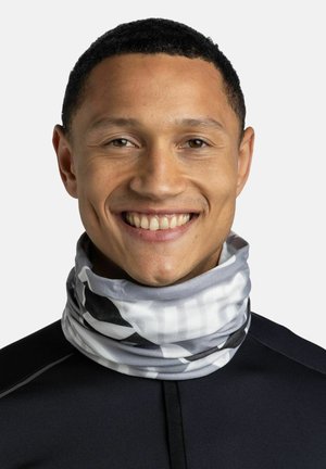 Gray and white patterned neck gaiter made of soft fabric, featuring a mix of stripes and abstract designs, worn by a smiling individual.
