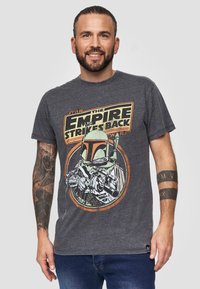 Camiseta de algodón gris con un gráfico vintage de Boba Fett y el texto "El Imperio Contraataca" en amarillo y rojo. Manga corta, cuello redondo.