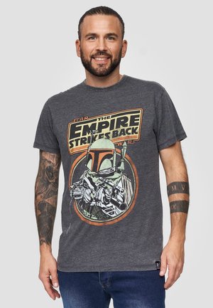 Grå bomulds T-shirt med et vintage grafik af Boba Fett og teksten "The Empire Strikes Back" i gul og rød. Korte ærmer, rund hals.