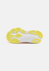 Semelle de chaussure avec une base blanche et un motif d'adhérence jaune vif, mettant en avant des rainures flexibles et le nom de la marque "Saucony" en relief.