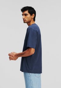 T-shirt en coton bleu marine à manches courtes, coupe décontractée et col ras du cou, associé à un pantalon à motifs bleu clair.