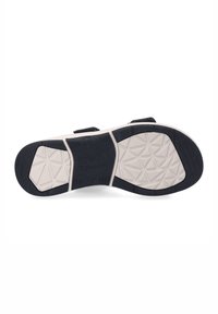 Czarna podeszwa sandałów z teksturowanymi wzorami i kremowymi akcentami, z grubą, konturowaną czarną bordurą i regulowanymi paskami.