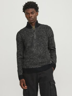 Pull en tricot noir et gris à motifs, avec un col zippé à quart et des poignets côtelés, associé à un pantalon cargo noir. Tissu texturé, de poids moyen.
