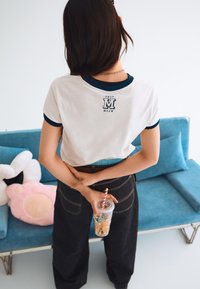 White short-sleeve t-shirt with navy blue trim, featuring a graphic "M" and the words "PREP MEOW" on the back. Dark baggy jeans.