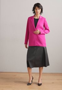 Fuchsia blazer with structured design, single-button closure, paired with a black leather A-line skirt and black high heels on a wooden floor.