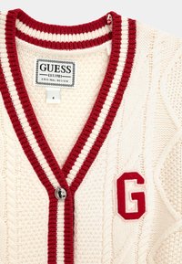 Cardigan en maille crème avec des rayures rouges et blanches le long du col en V, doté d'un bouton rond argenté et d'un logo "G" rouge brodé sur la poitrine.