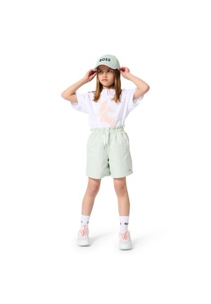 Shorts vert clair avec taille élastique, t-shirt blanc avec "BOSS" en rose et casquette bleu clair avec "BOSS" en lettres bleu foncé.