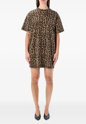 Donna che indossa un vestito largo a maniche corte con stampa leopardata abbinato a tacchi neri a punta, in piedi con le braccia rilassate lungo i fianchi.