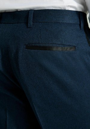 Granatowe spodni teksturowane o slim fit. Posiadają czarny akcent na tylnej kieszeni i gładki pas.