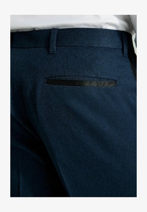 Pantalons texturés bleu marine à coupe slim. Présente un accent noir sur la poche arrière et une taille lisse.