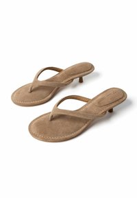 Paire de sandales beige en daim à brides en T avec petits talons kitten, bouts arrondis et bords cousus sur fond blanc.