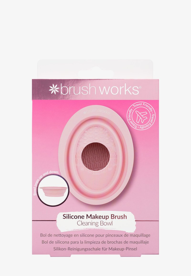 Silikone sminkebørste rengøringsskål i lys pink, oval form med struktureret indre og forhøjet greb, pakket med klar branding og rejseindikator.