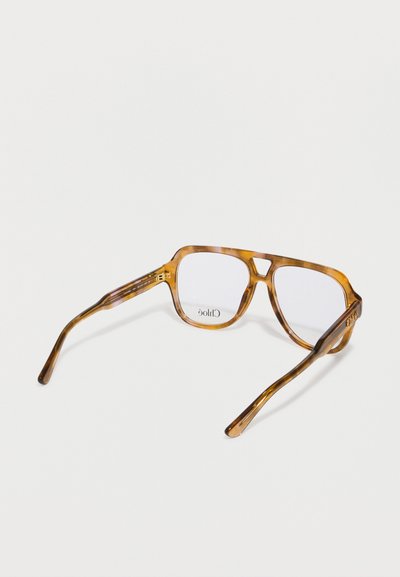 Akiniai nuo saulės su vėžlio kiauto raštu, skaidriais lęšiais, stačiakampio formos ir plonomis kojelėmis. „Chloé“ prekės ženklas matomas ant rėmo vidinės pusės.