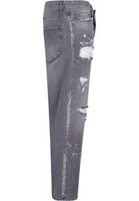 Jeans de mezclilla gris de corte holgado, con múltiples áreas desgastadas, bordes deshilachados y manchas de pintura ligeras. Diseño de cinco bolsillos.