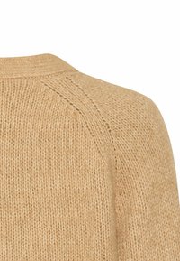 Beige gestrickter Pullover mit Rundhalsausschnitt und Raglanärmeln, der eine strukturierte Oberfläche aufweist und das weiche, warme Material betont.