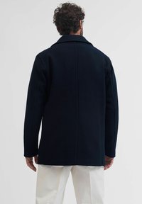 Navy wollen jas met een gestructureerd ontwerp, brede revers en rechte snit. Heeft strakke lijnen en een gladde textuur, gezien vanaf de achterkant.