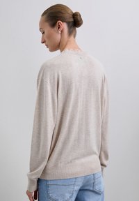 Suéter beige de punto con dobladillo y puños acanalados, que presenta un sutil diseño texturizado y un escote redondeado. Vista trasera mostrada.