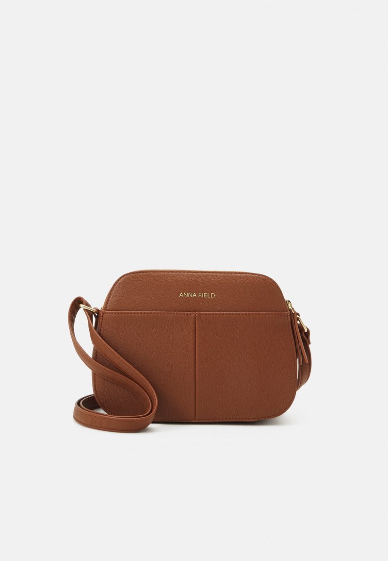 Brun faux læder crossbody taske med en glat overflade, rektangulær form, lynlåslynlås i toppen og logo detaljer i guldtoner. Justerbar rem.