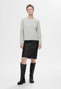 Grijze sweatshirt met lange mouwen, zwarte leren kokerrok en kniehoge zwarte laarzen. Glad textuur met een getailleerde silhoeet.
