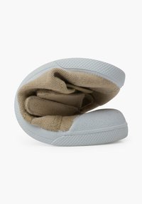 Chaussure en toile pliée avec une tige en textile beige, embout en caoutchouc gris et semelle. Texture lisse avec un motif légèrement en relief sur la semelle.