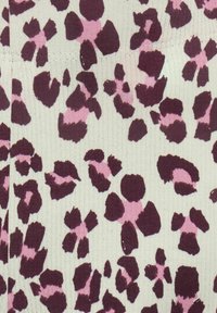 Strikket stof med en hvid baggrund, der har et leopardmønster i mørk burgunder og blød lyserød, med varierende former og størrelser af pletter.