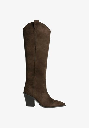 Bota cowboy de ante marrón con punta afilada y tacón de bloque de altura media. Presenta costuras decorativas a lo largo del caño y una lengüeta para ayudar a calzarlas.